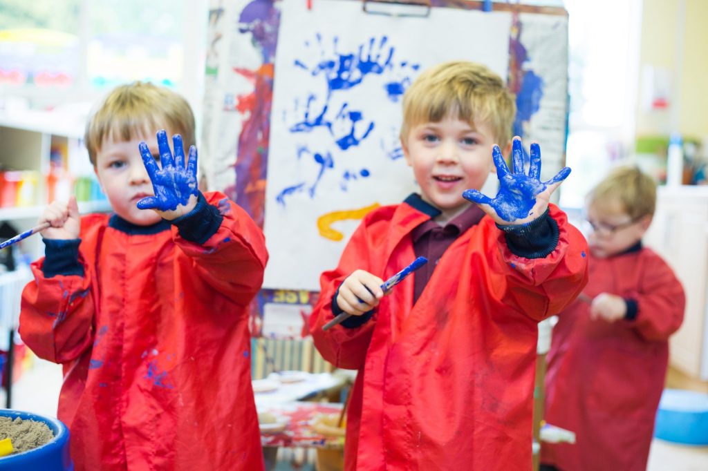 two boys showing their hands with blue paint on them