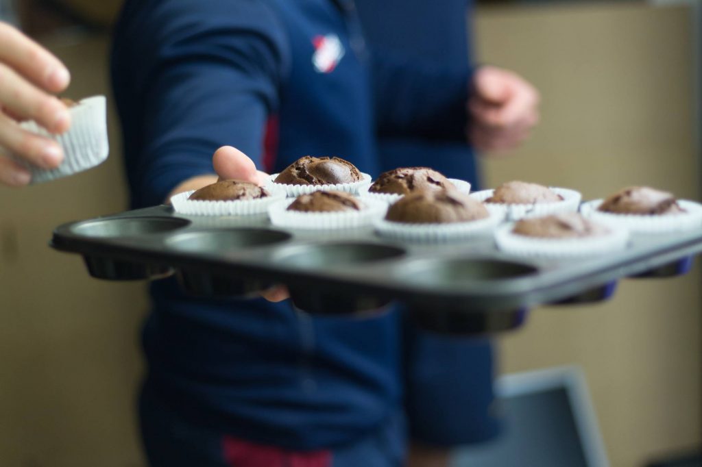 student with a tray of muffins